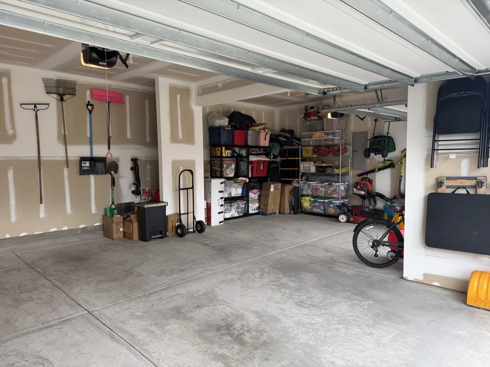 After organizing: filled storage shelves, wall-mounted yard tools, and clear garage floor space