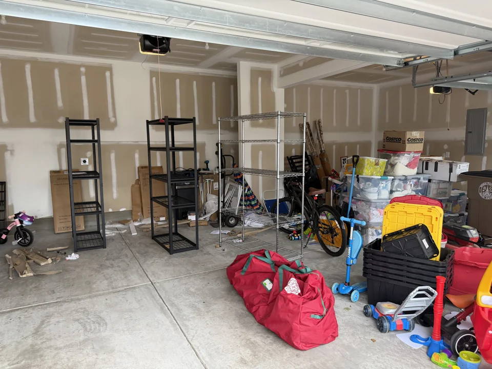 Before organizing: belongings and empty shelving spread across the garage floor