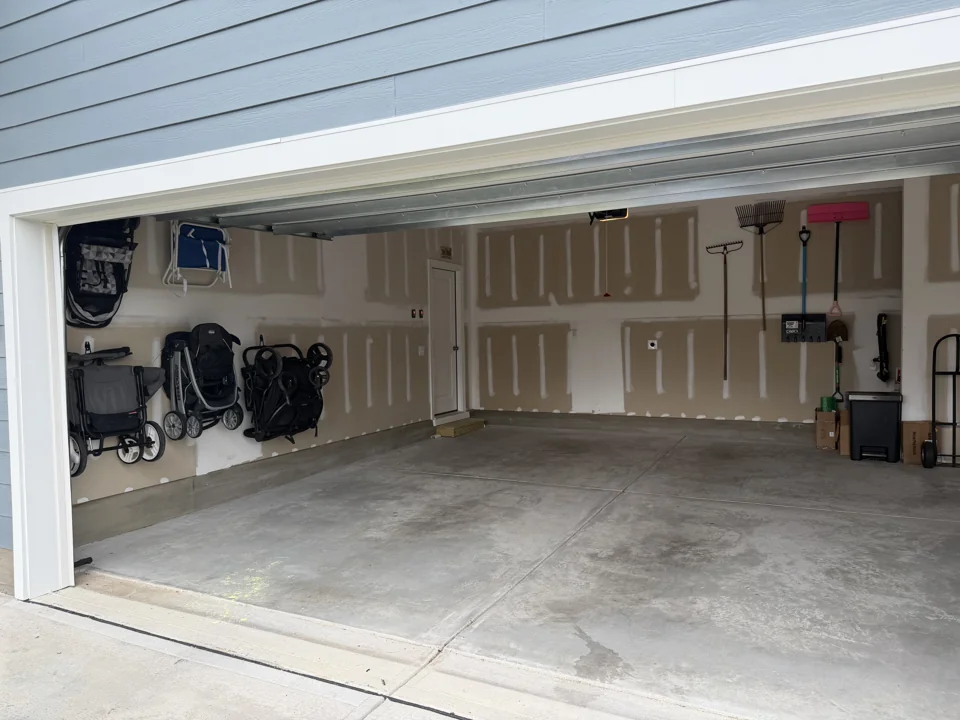 Strollers mounted on the wall and the garage floor cleared after organizing